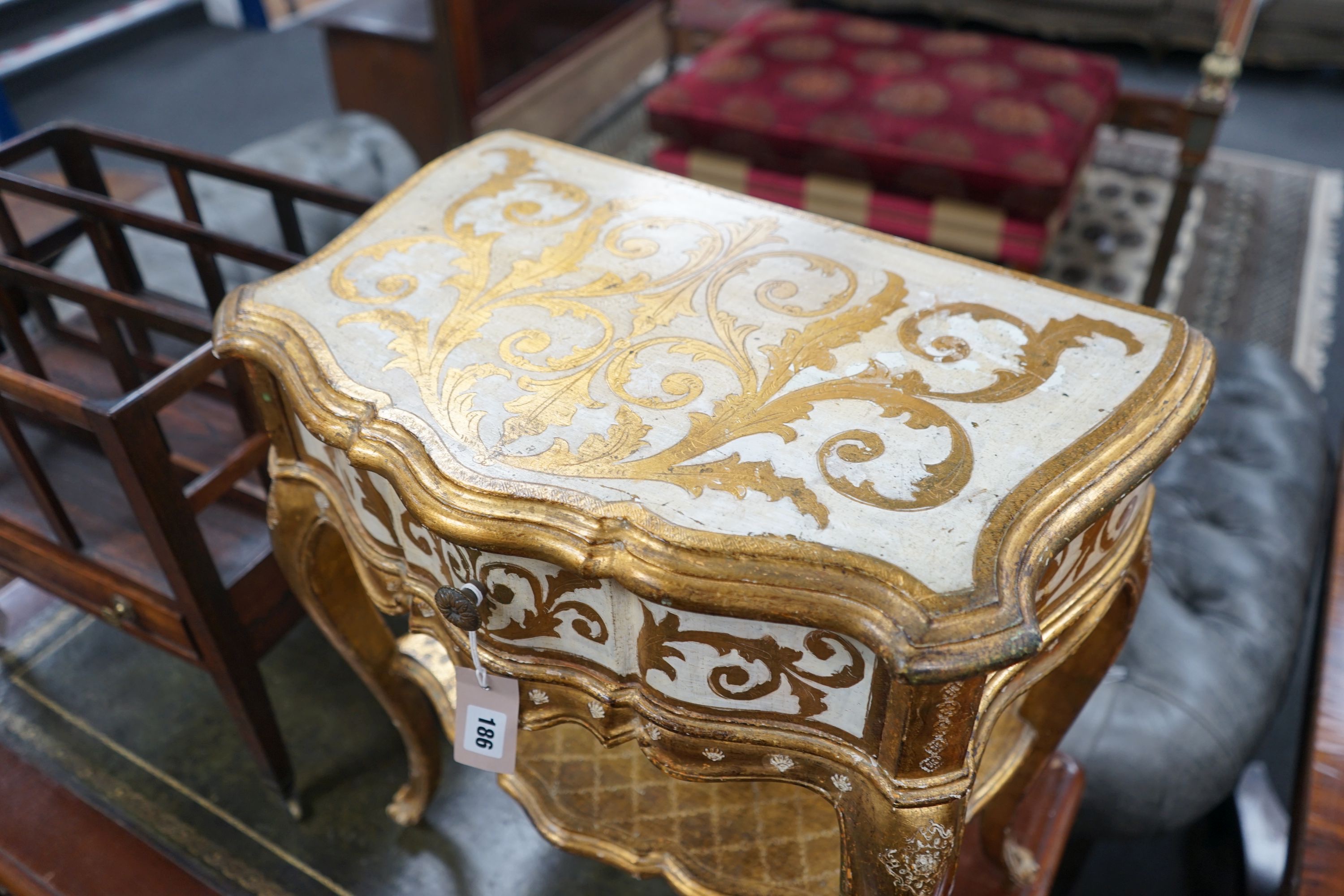 A Florentine gilt and cream painted serpentine two tier side table, width 50cm, depth 34cm, height 58cm